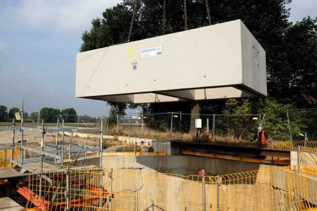 Ablassen der Doppelkammer-Fertigteile mit rd. 44 t Einzelgewicht in die Schlitzwandbaugrube. Das Fertigteilwerk hatte in Anlehnung an das Konzept der Düker-Vortriebsrohre eine SW-Beton-Rezeptur erarbeitet.