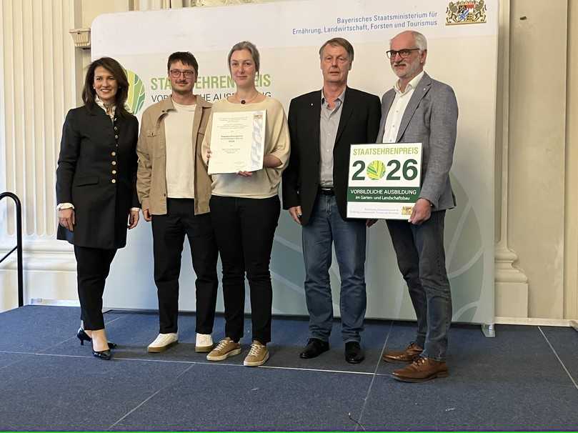 Bei der Verleihung des Staatsehrenpreises 2026: Dietmar Lindner (rechts) mit der bayerischen Staatsministerin Michaela Kaniber (links) und einer Delegation der Firma H&M Gartengestaltung. | Foto: VGL Bayern
