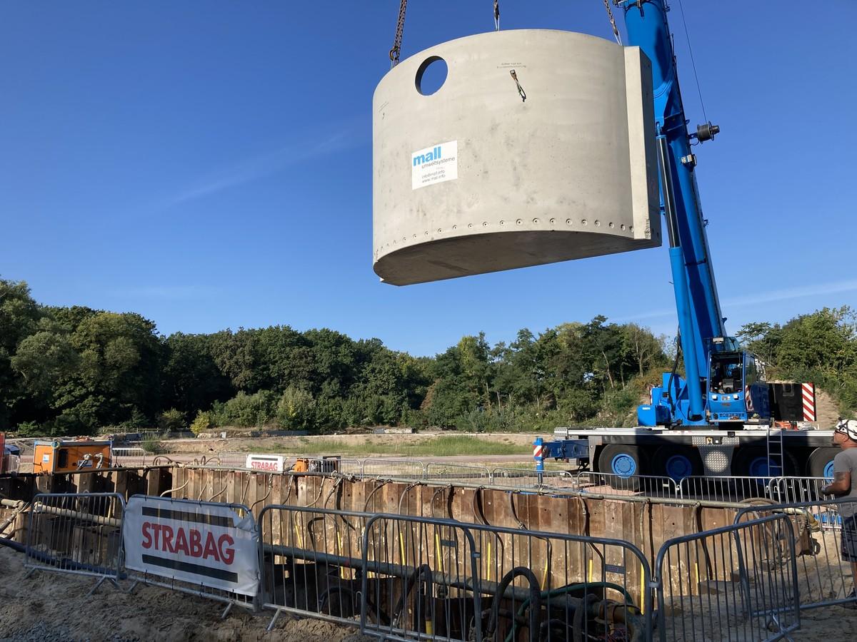 Ein Stahlbetonelement des kleineren Speicherbehälters (50 m³) wird in die Baugrube herabgelassen. | Foto: Mall