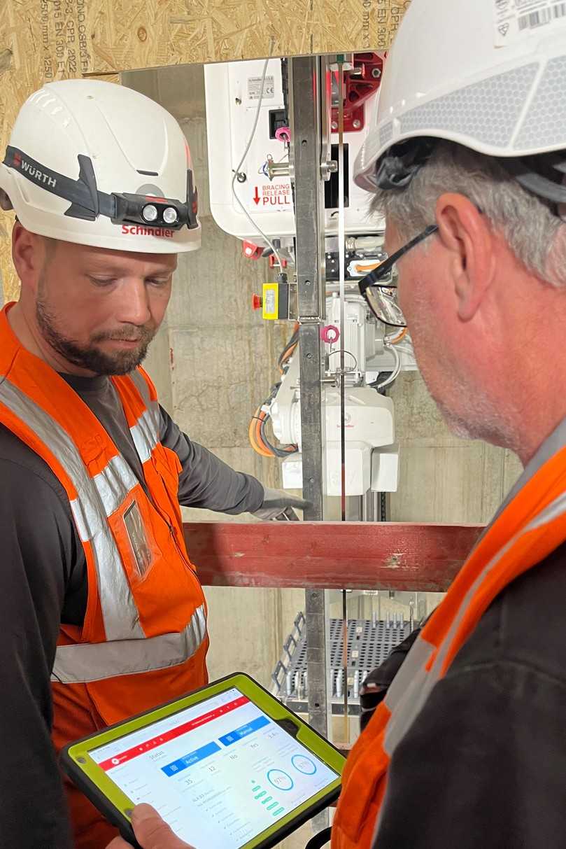 Aufzugsmonteur und ein Schindler „R.I.S.E“-Operator auf der Baustelle des 030BLN: Die Arbeiten des Installationsroboters werden lückenlos überwacht und ausgesteuert. | Foto: Schindler Deutschland