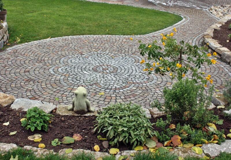Vom Handwerk zur Kunst: Rosette mit Mosaikpflaster neben Trockenmauer. Vom Handwerk zur Kunst: Rosette mit Mosaikpflaster neben Trockenmauer.