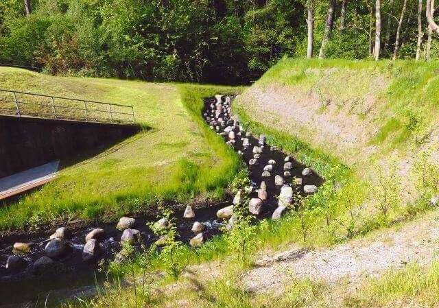 Gewässersohle und Böschung sind bis zur mittleren Höhe (ca. 2 m) mit Steinmatratzen gesichert. Die Neigung geht bis auf 70° und schützt diesen kritischen Böschungsbereich. Gewässersohle und Böschung sind bis zur mittleren Höhe (ca. 2 m) mit Steinmatratzen gesichert. Die Neigung geht bis auf 70° und schützt diesen kritischen Böschungsbereich.
