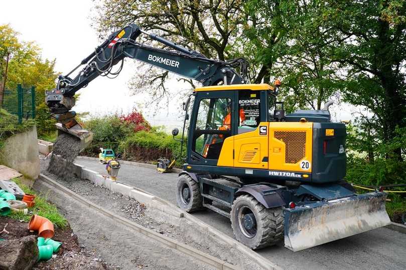 Mobilbagger beim Wegebau in Waldenburg. Der Fahrer muss Splitt feinfühlig zur Vorbereitung der neuen Gehwege an einer Pumpstation verteilen. | Foto: Hyundai/OBA