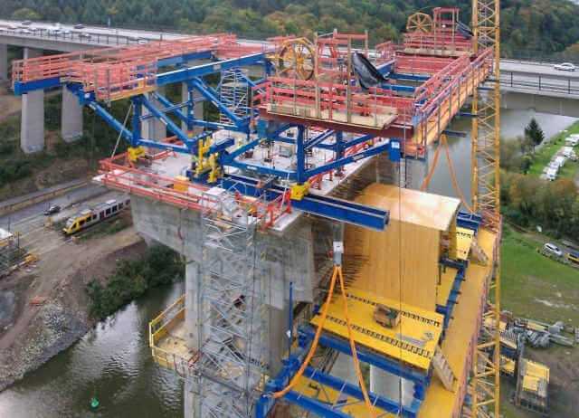 Doka konstruierte aus Bögl-Eigenmaterial eine spezielle Litzenheberbühne für den Freivorbau. Damit waren die Bodenroste ohne große Autokrane direkt vom Boden hochzuziehen. Doka konstruierte aus Bögl-Eigenmaterial eine spezielle Litzenheberbühne für den Freivorbau. Damit waren die Bodenroste ohne große Autokrane direkt vom Boden hochzuziehen.