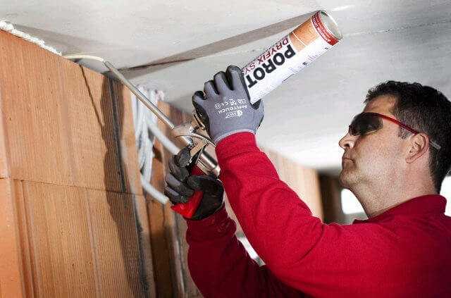 Ein spezieller Deckenanschluss-Kleber verbindet kraftschlüssig die Stahlbetondecke mit den nichttragenden Innenwänden. Für Fugen größer als 20 Millimeter wird die Klebepistole des Dryfix-Systems verwendet. Bei schmaleren Fugen hilft eine spezielle Schlauchverlängerung. | Foto: Deutsche Poroton / Sandra Göttisheim Ein spezieller Deckenanschluss-Kleber verbindet kraftschlüssig die Stahlbetondecke mit den nichttragenden Innenwänden. Für Fugen größer als 20 Millimeter wird die Klebepistole des Dryfix-Systems verwendet. Bei schmaleren Fugen hilft eine spezielle Schlauchverlängerung. | Foto: Deutsche Poroton / Sandra Göttisheim