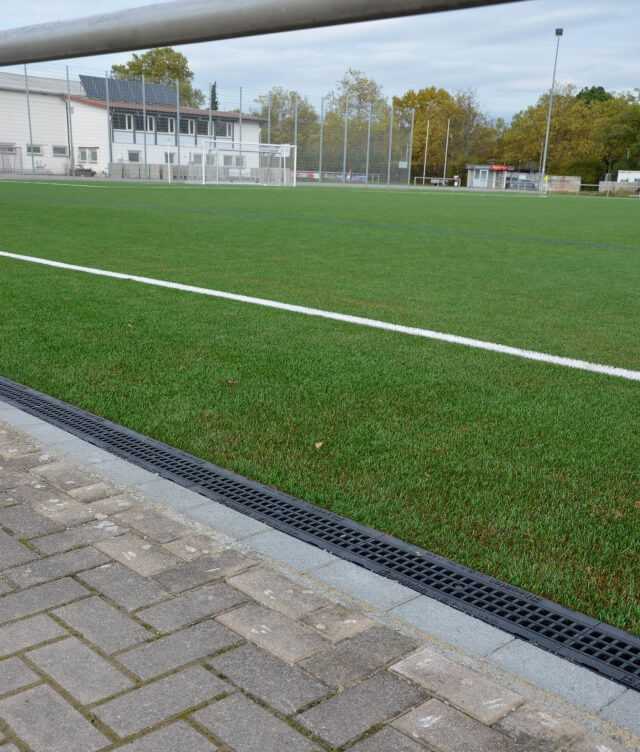 An den Einlaufkästen beginnend, wurden die Rinnenstränge entlang des Spielfeldrandes auf ein Betonfundament gesetzt und mit einer Rückenstütze aus Beton stabilisiert.