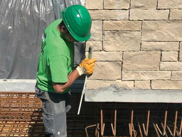 Setzen einer schweren Winkelstützwand. Ist sie fixiert, wird ihre Anschlussbewehrung mit der vorhandenen Armierung im Fertigteilfundament verbunden und mit Ortbeton vergossen.