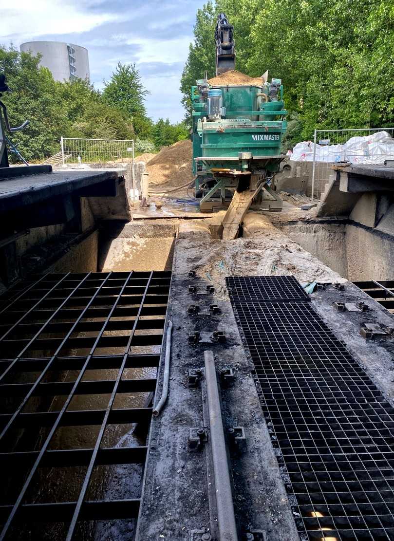 Der am Kopfende stehende, höhenverstellbare Bagger belädt die mobile Mischanlage mit dem Grundmaterial. Nach einer angepassten Mischzeit wird das Material als Flüssigboden in den aufzugebenden Bunker entlassen. | Foto: Flüssigboden SH Der am Kopfende stehende, höhenverstellbare Bagger belädt die mobile Mischanlage mit dem Grundmaterial. Nach einer angepassten Mischzeit wird das Material als Flüssigboden in den aufzugebenden Bunker entlassen. | Foto: Flüssigboden SH
