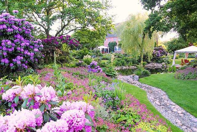 Der Blick in die andere Richtung auf das Haus zeigt die relativ frisch verpflanzten Rhododendren links und die verbesserte Bodenmodellierung samt Trockenbachlauf rund um den neuen Teich.