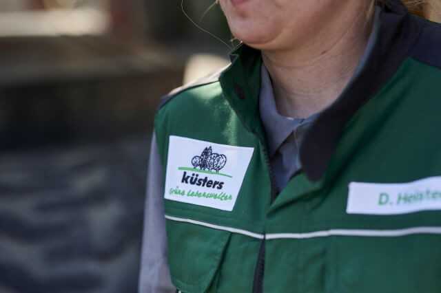 Die Arbeitskleidung ist mit Unternehmenslogo und Mitarbeiternamen versehen.