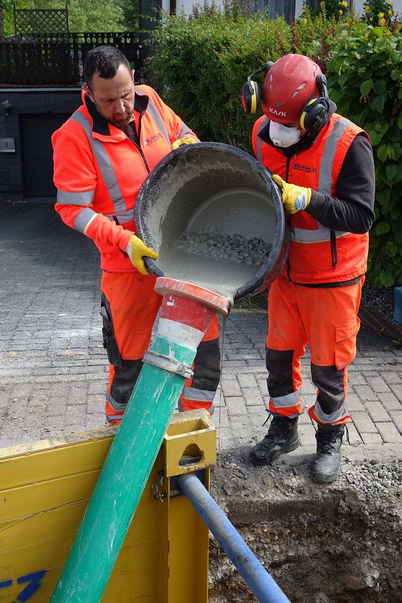 Thomas Sy (re.) und Tom Textor von der Betriebskolonne der Gemeindewerke Burbach beim Einbringen des fließfähigen Ombran MC FG plus-Vergussmörtels über ein Kunststoffrohr | Foto: Preco