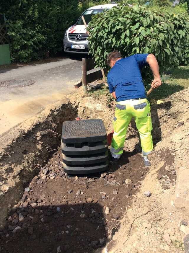 Der Graben wird mit Sand und Split verfüllt. Durch das höhenverstellbare Oberteil kann der Schacht individuell z.B. an die Neigung der Straßenoberfläche ausgerichtet werden.
