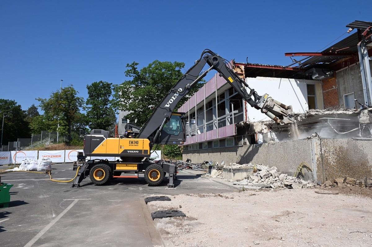 Der Volvo Umschlagbagger EW240 Electric MH hängt am Stromkabel und reißt emissionsfrei das Siemens-Gebäude in Erlangen ab. | Foto: QUATEX