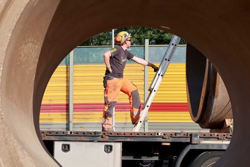 Einblick in die Dimensionen: Ein Mitarbeiter auf einem der Lkw, gesehen durch eines der zwei Meter hohen Polymerbetonrohre. | Foto: Meyer-Polycrete