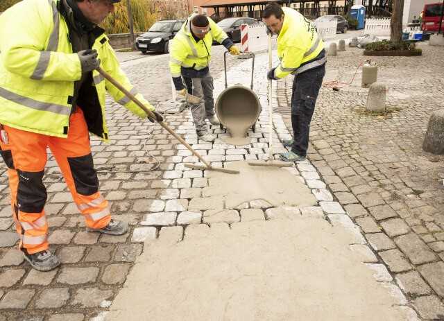 Der mineralische, schnellerhärtende und schwundneutrale Reparaturmörtel „Mortar Mix“ wird durch Zugabe von Wasser verflüssigt und in die zu bearbeitende Kopfsteinpflasterfläche eingeschwemmt. | Foto: Korodur