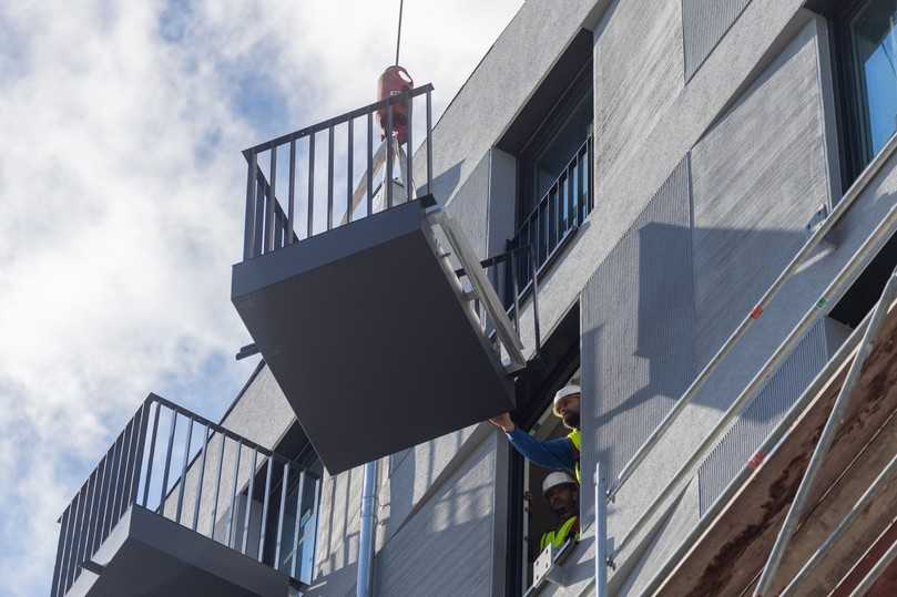 Ein Balkon wird vom Kran an die Fassade gehoben. Die Montage konnte schnell und aufgrund der hohen Wiederholungsrate sehr zeiteffizient erfolgen. | Foto: Schöck Bauteile GmbH